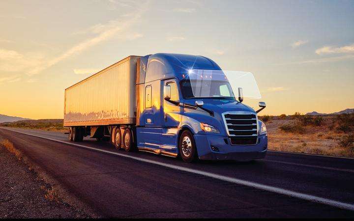 Truck driving down country road at sunset