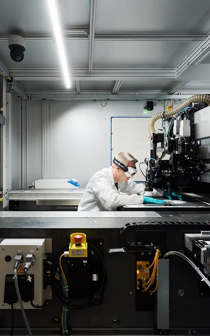 Man wearing safety goggles working on a machine in a production facility