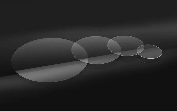 Four clear circular samples of SCHOTT MEMpax® thin borosilicate glass on a black background