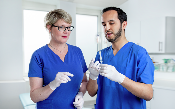 Medical staff, woman and man with plastic syringe.