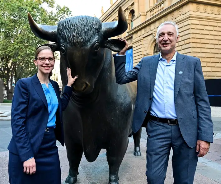 A woman and a man stand in front of a bull statue.
