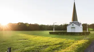 Two solar-powered street lights next to monument in green field 