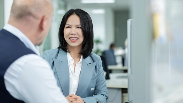 Jocelyn Jiang sitting at a desk and talking to Folker