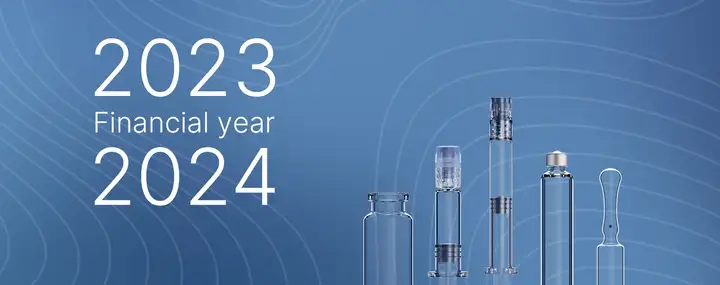 Graphic with "Fiscal year 2023/2024" text and a lineup of pharmaceutical glass products, including vials, syringes, and ampoules, on a blue patterned background.