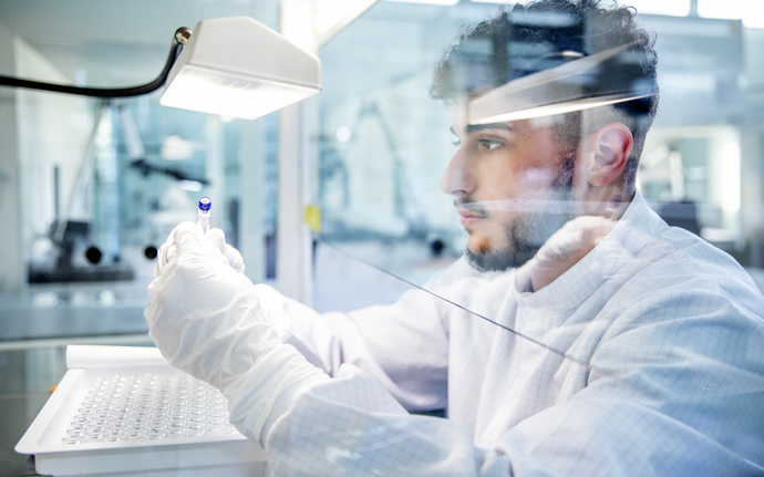 An employee in the clean room holds a prefillable glass syringe in his gloved hand for testing.