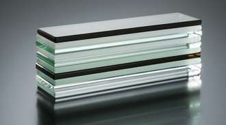 Stack of  glass sheets with different colors and edges, arranged horizontally on a reflective surface.