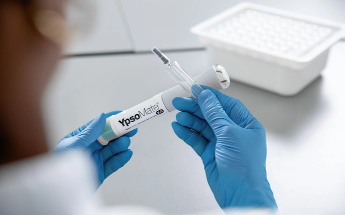 Woman holding a large-volume syriQ BioPure® 5.5 ml glass syringe with the YpsoMate® 5.5 auto-injector from Ypsomed.