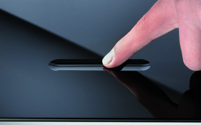 Finger running along a groove in a black panel of glass 