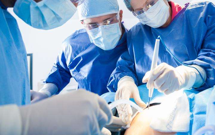 Team of surgeons in an operating theater performing a light-based medical therapy