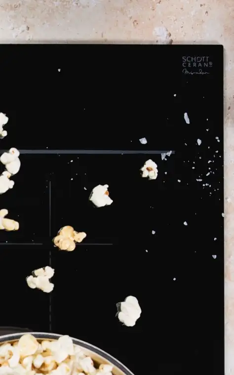 Top view of a SCHOTT CERAN® Miradur cooktop with scattered popcorn and meal preparation ingredients arranged on the countertop.