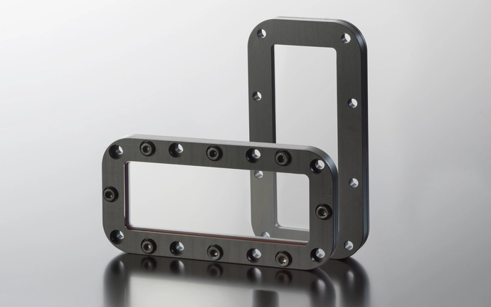 Two rectangular protective windows with bolt holes displayed together.