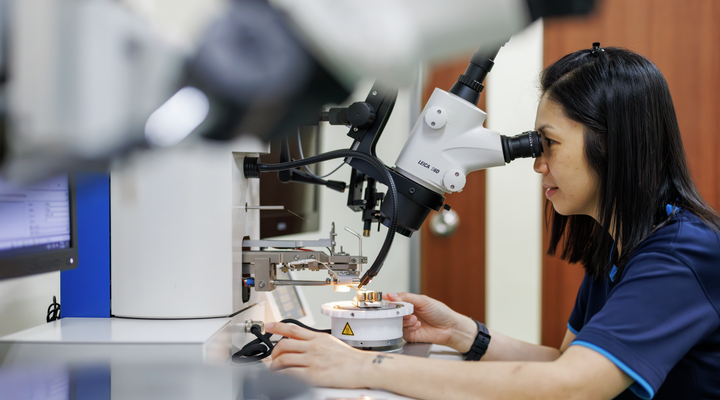 Quality engineer looking at components through a microscope.  