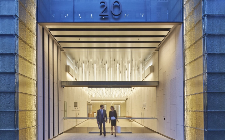 Man and woman leaving an office building with a SCHOTT glass installation filled with light