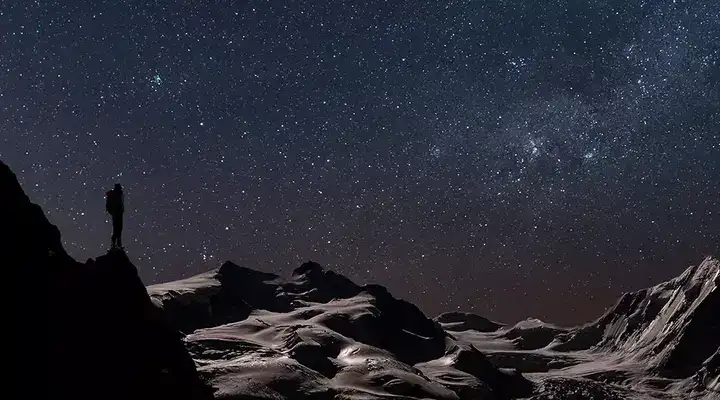 Explorer looks out across a space landscape at night