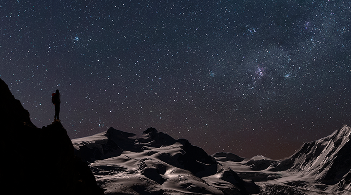 Explorer looks out across a space landscape at night
