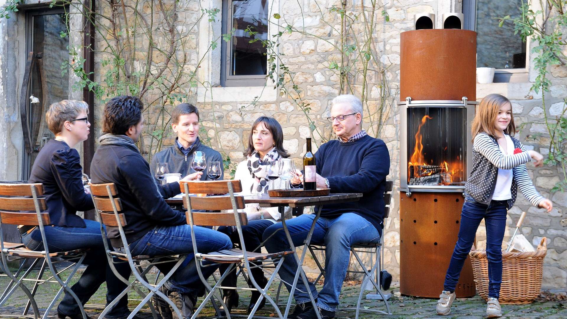 Family seated at an outdoor table with fireplace