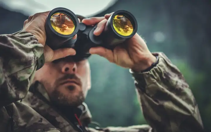 Man looking through a pair of high powered binoculars in daytime