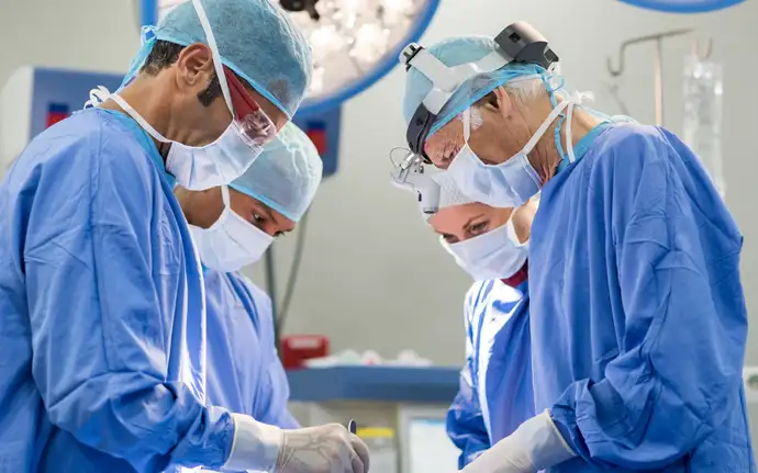 Four medical professionals perform an operation in a hospital