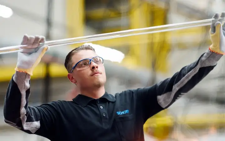 Male engineer inspecting a length of clear glass tubing