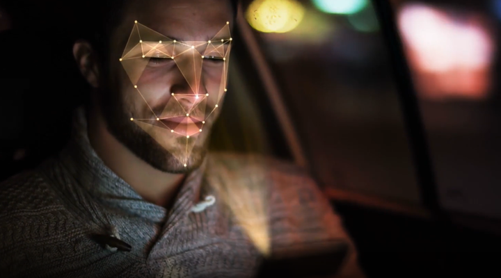 Man in a car looking at a smartphone with face-mapping technology