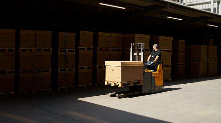 Man on a forklift transporting goods into a warehouse