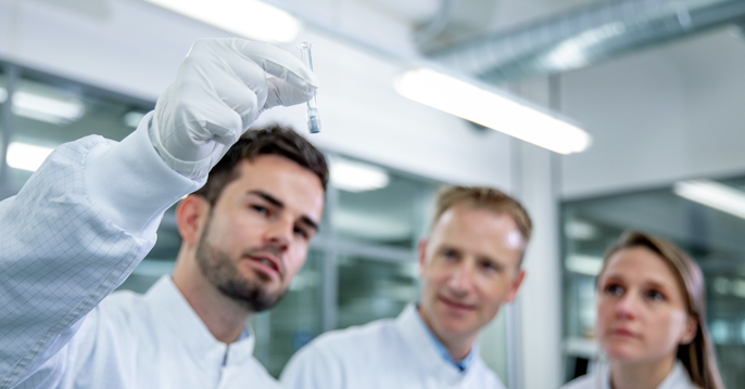 Group of lab workers looking at syringe for visual inspection check