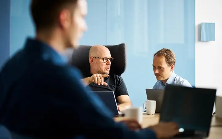 Three men in a conference room engaged in a collaborative working session