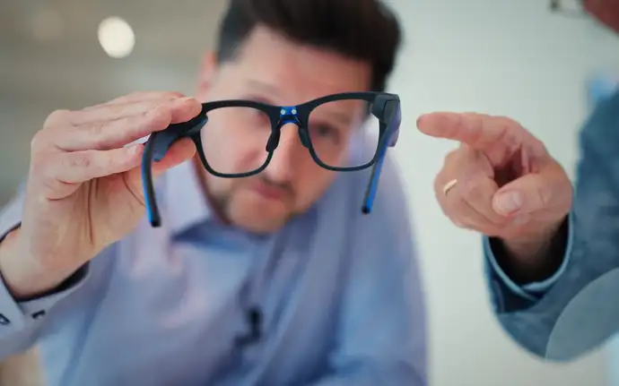 Mann hält eine AR-Brille in den Händen und schaut hindurch.