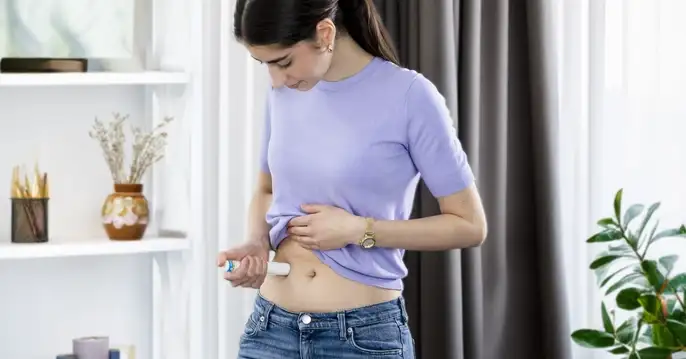 Women sitting in living room injecting drug via large-volume autoinjector.