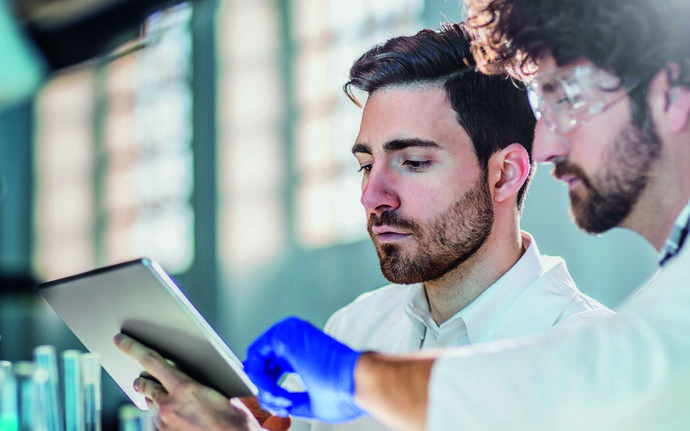 Two male scientists looking at a tablet display