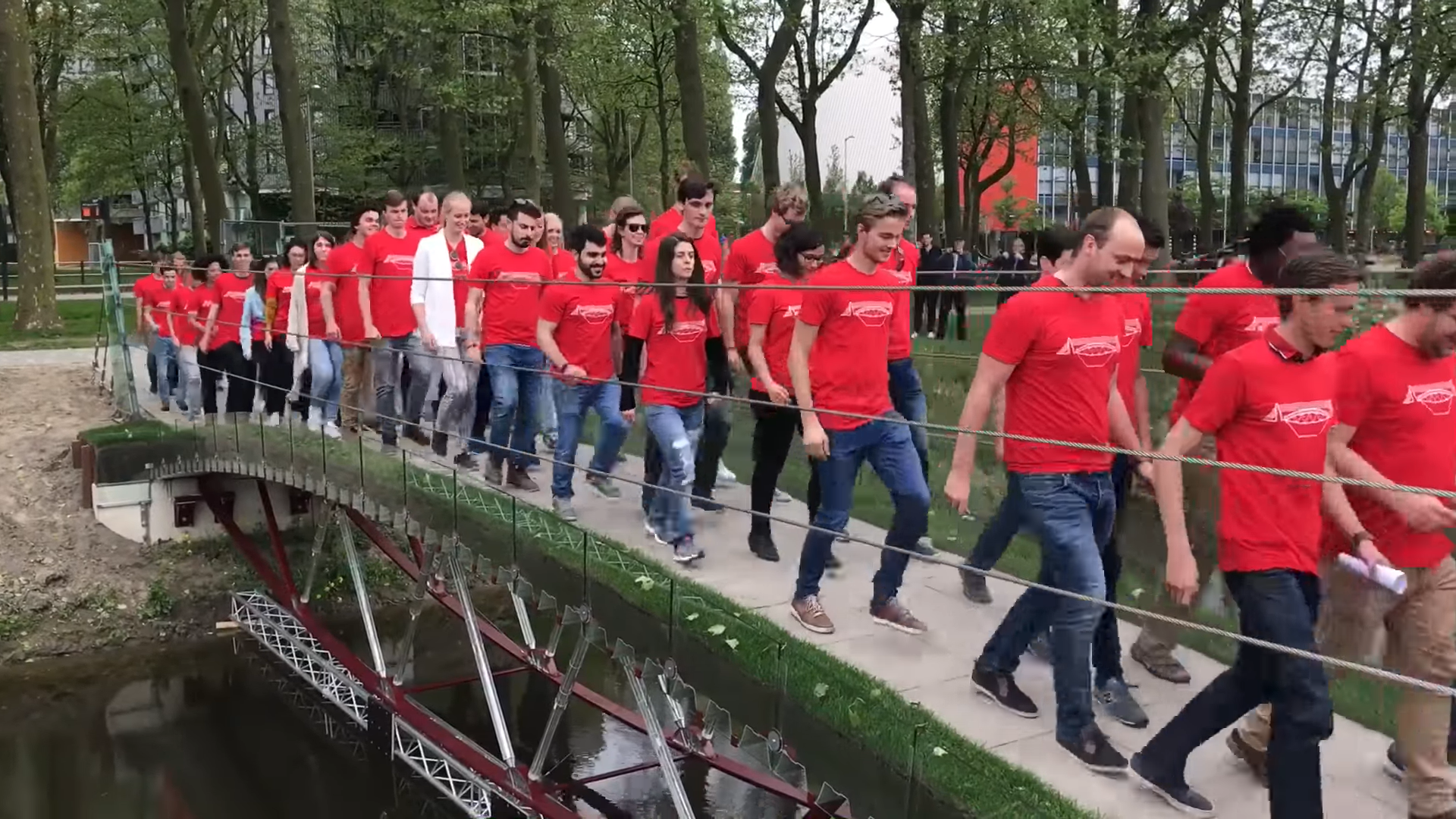 Des étudiants en T-shirts rouges traversant le pont en verre de l’Université de Technologie de Delft, aux Pays-Bas
