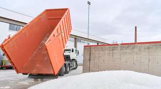 The container is tipped so that the load falls onto a yard on which a mountain of Fiolax vials is already sitting	