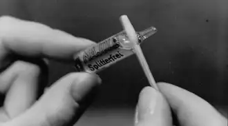 Black and white image of hands holding glass ampoule from 1923