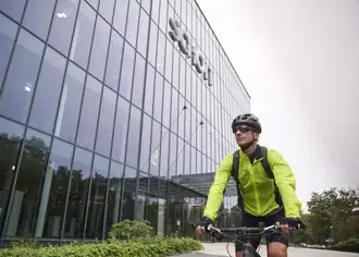 Michael Hahn arrives at SCHOTT in Mainz by bike, wearing a bright green jacket