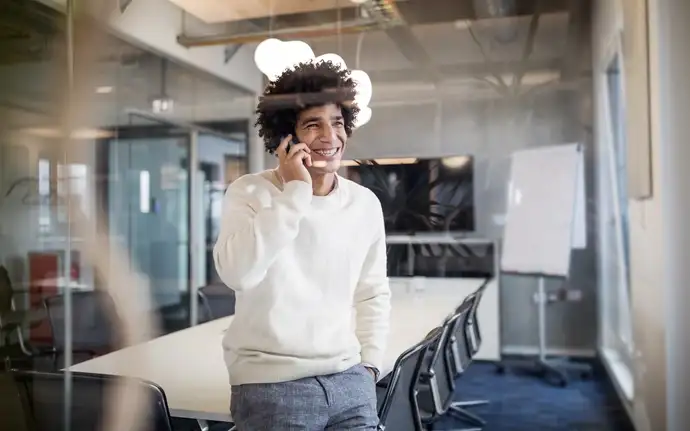 Jovem ao telefone em uma sala de reuniões corporativa