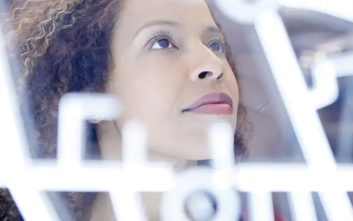 Female looking at illuminated lines on glass panel 