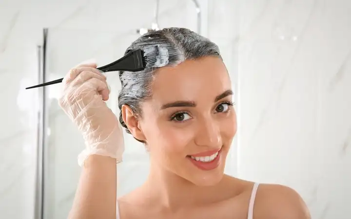 Smiling woman applying permanent hair color