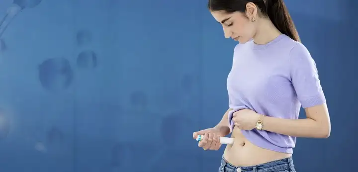 Women holding autoinjector in right hand, injecting medication.