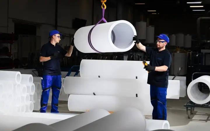 Two SCHOTT employees transport a large cylindrical quartz glass component