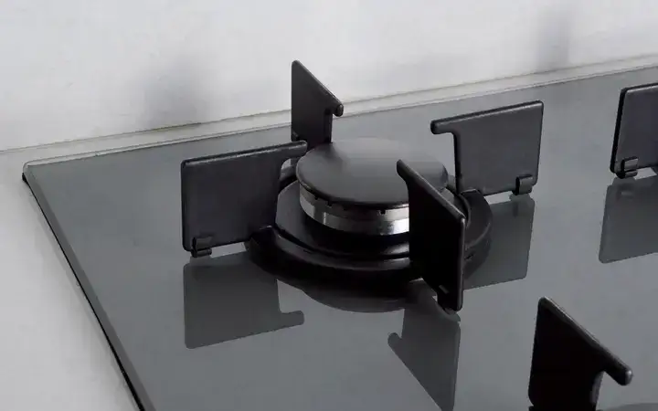 Close-up of a gas burner on a glass stove top