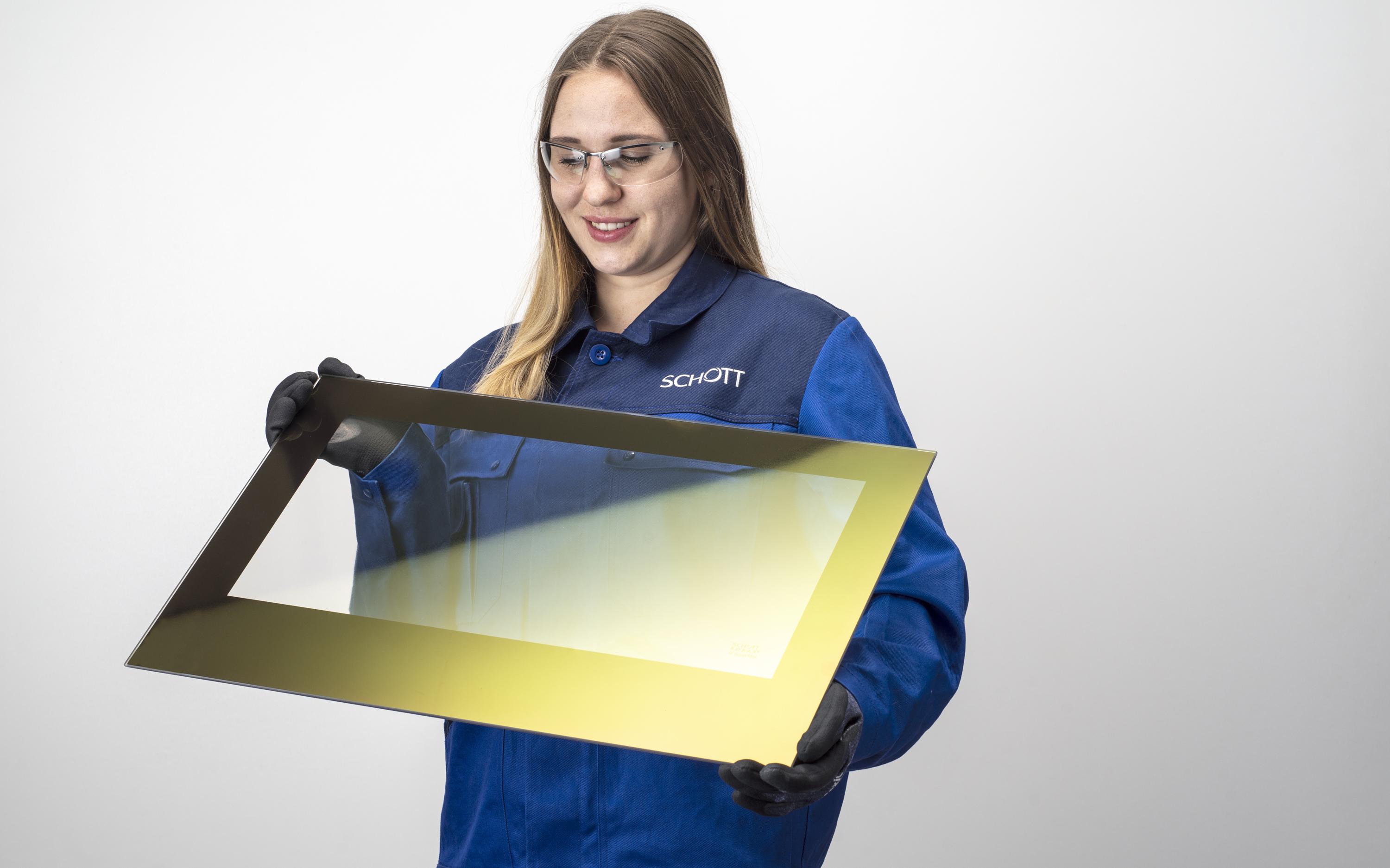 Female SCHOTT engineer inspecting a glass-ceramic panel coated with ROBAX® IR SuperMax