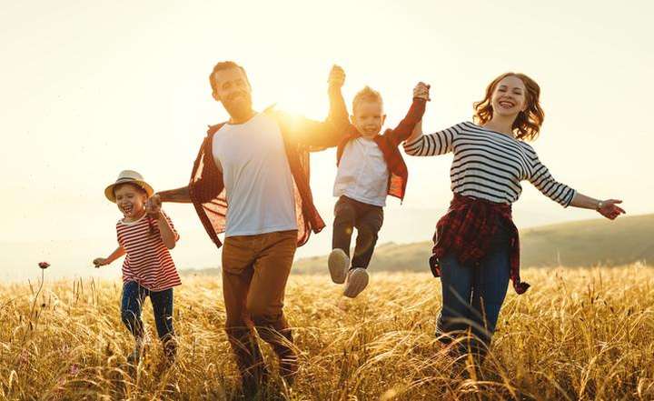 Young family running through a wheat field in sunshine