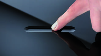 Finger touching a groove in a black glass panel