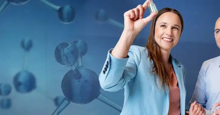 Man and woman look at a pharmaceutical vial infront of moleculs