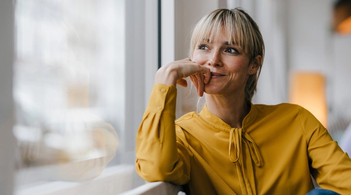 Female in a yellow blouse gazing out of a window