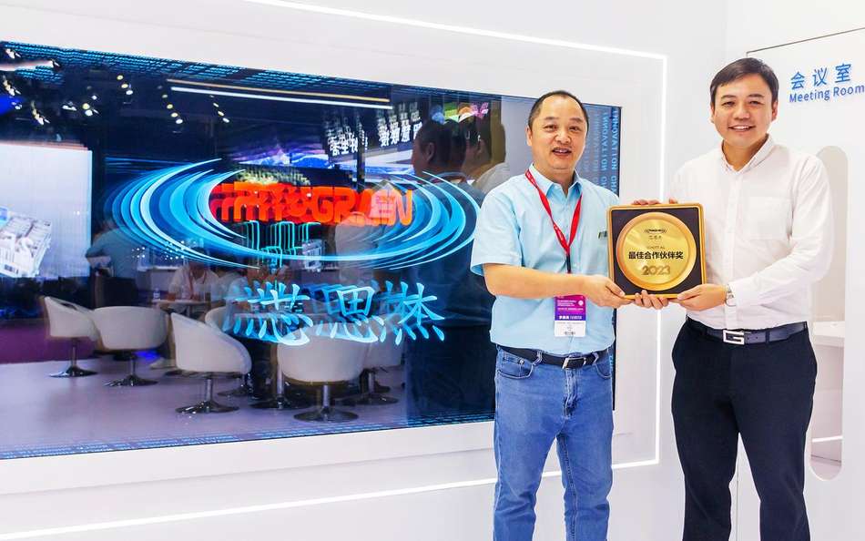 Two men hold Phograin's Best Partner Award. In the background the Phograin logo.