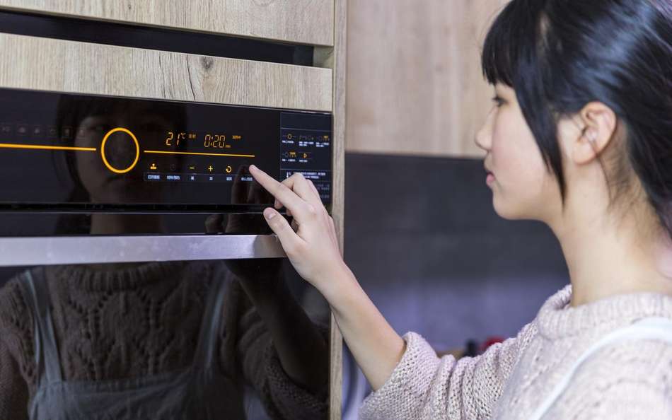 Mujer utilizando el panel de mando táctil de un horno