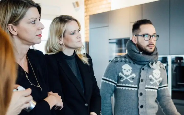 Two women and a man are being informed about vitroceramic cooktops from SCHOTT CERAN® at an event