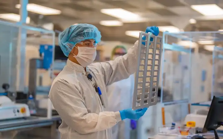 Scientist in a laboratory holding a glass substrate frame.