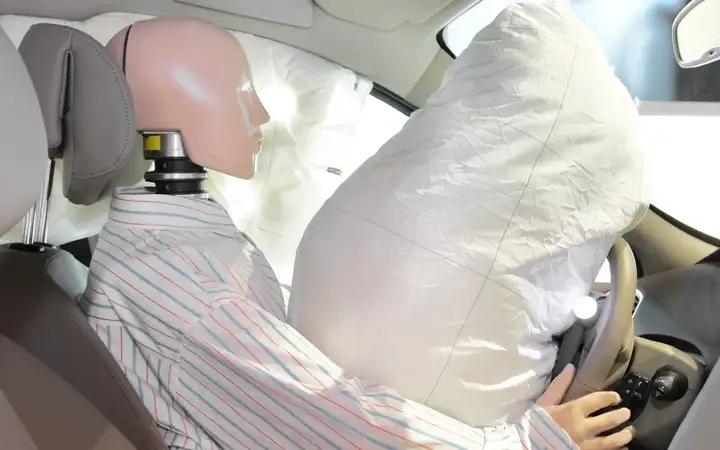 Crash test dummy in vehicle with inflated airbag